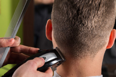 airdresser cutting clients hair with an electric hair clipper at beauty salon on board