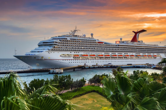 ruise ship Carnival Conquest docked at port Willemstad on sunset. The island is a popular Caribbean cruise destination